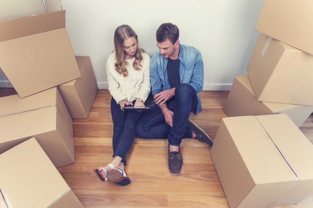 Young couple sitting in new house with packing boxes.